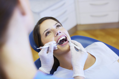 A pretty young woman with a bright, white smile lying in the dentist's chair having a checkup